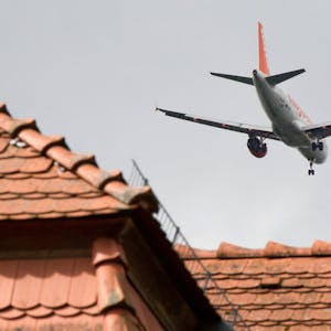 Ein Flugzeig fliegt über ein Hausdach (Symbolbild)