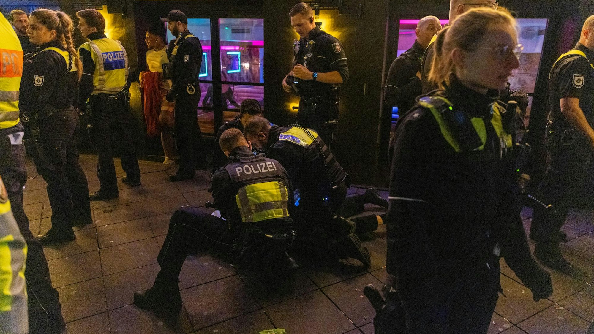 Polizisten fixieren einen aggressiven Mann am Boden.