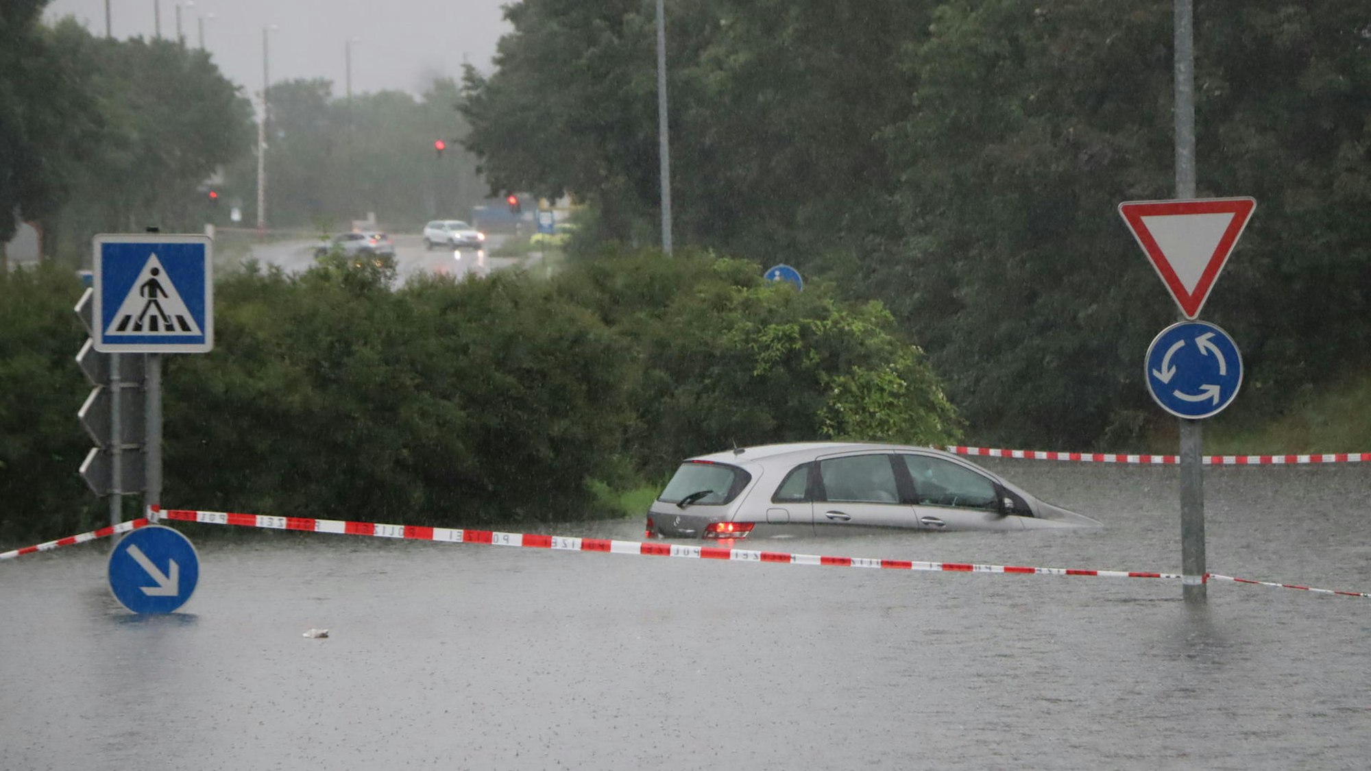 Ein Auto ist aufgrund der Überschwemmung nur halb zu sehen, der Rest ist unter Wasser. Mehrere Verkehrsschilder ragen aus dem Wasser. (Archivbild)