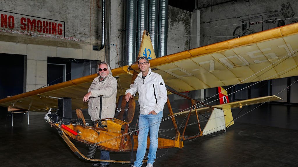 Tommy Engel steht neben Marc Metzger an einem alten Holzflugzeug