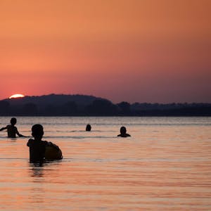 Kinder beobachten den Sonnenuntergang im Achterwasser der Insel Usedom.