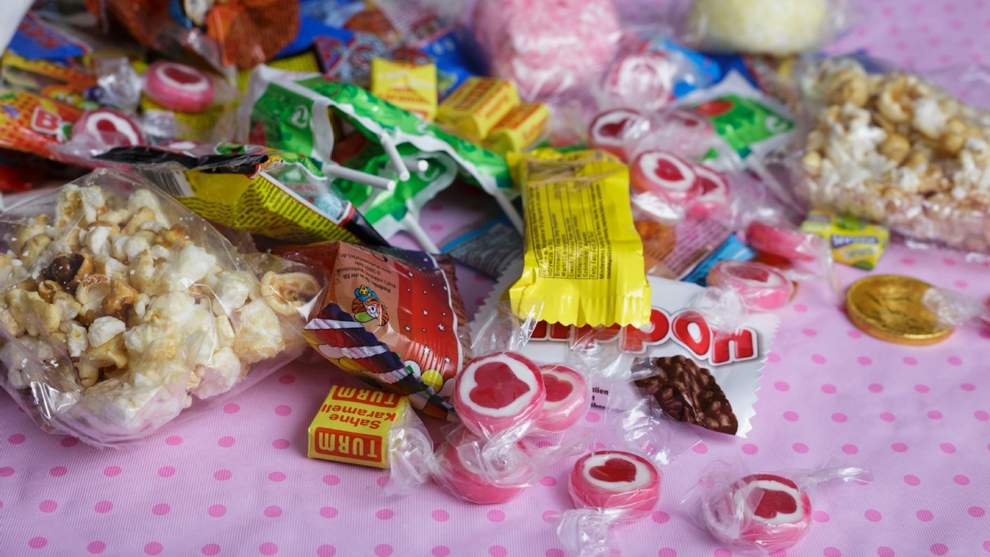 verschiedene Süßigkeiten liegen auf einer rosanen Tischdecke