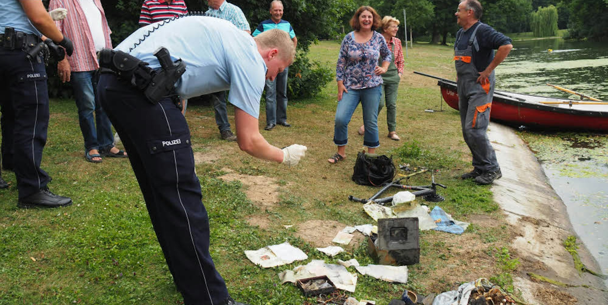 Die Polizei dokumentiert die Fundstücke, die Taucher im Weiher gefunden haben.