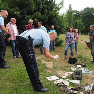 Die Polizei dokumentiert die Fundstücke, die Taucher im Weiher gefunden haben.