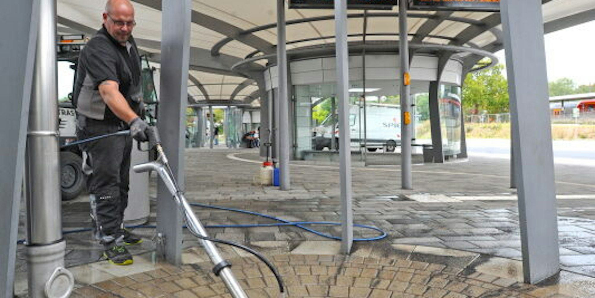 Mitarbeiter einer Fremdfirma reinigt die verdreckten Platten am Busbahnhof.