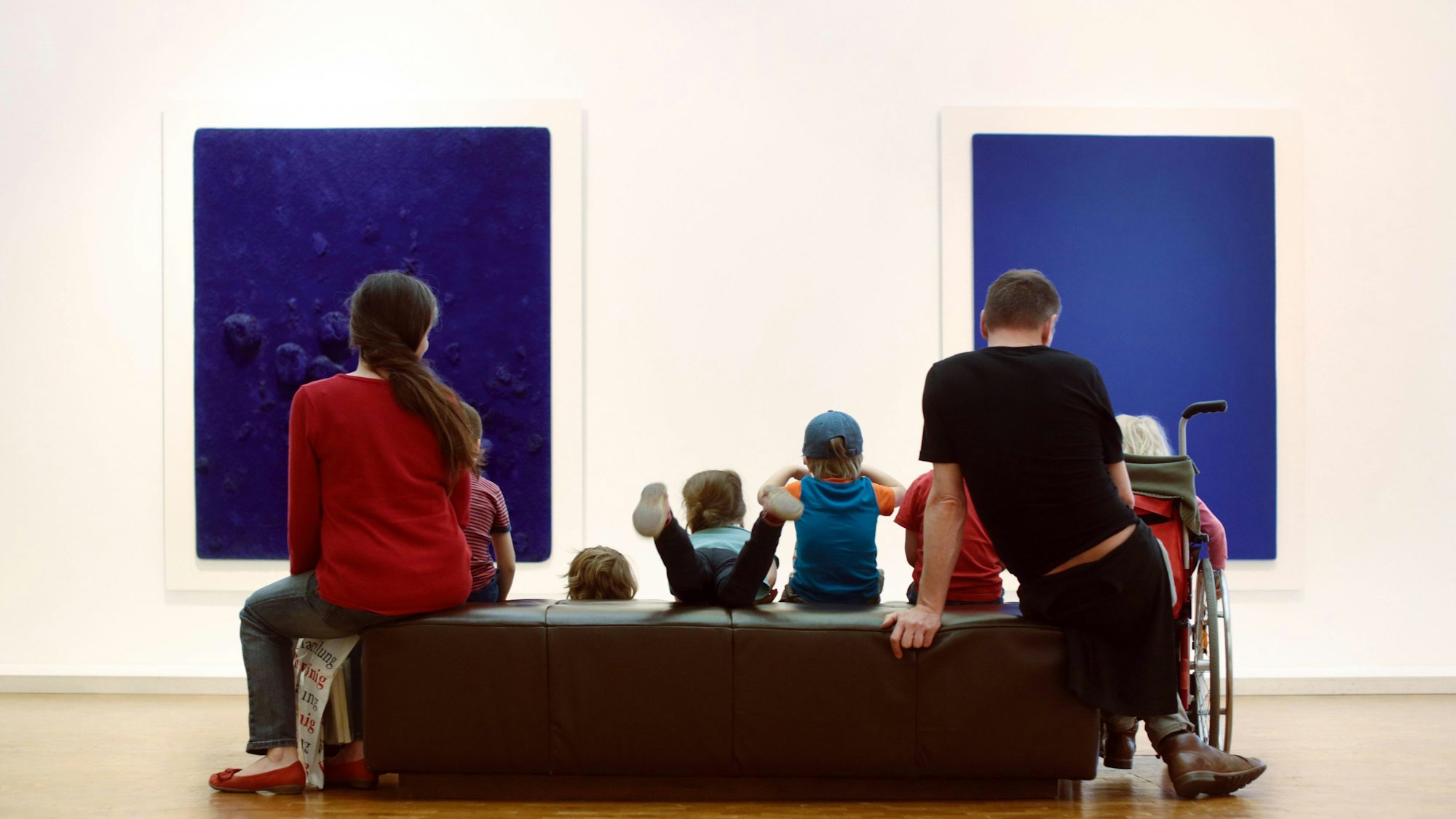 eine Familie sitzt auf einem Sofa vor zwei blauen Bildern