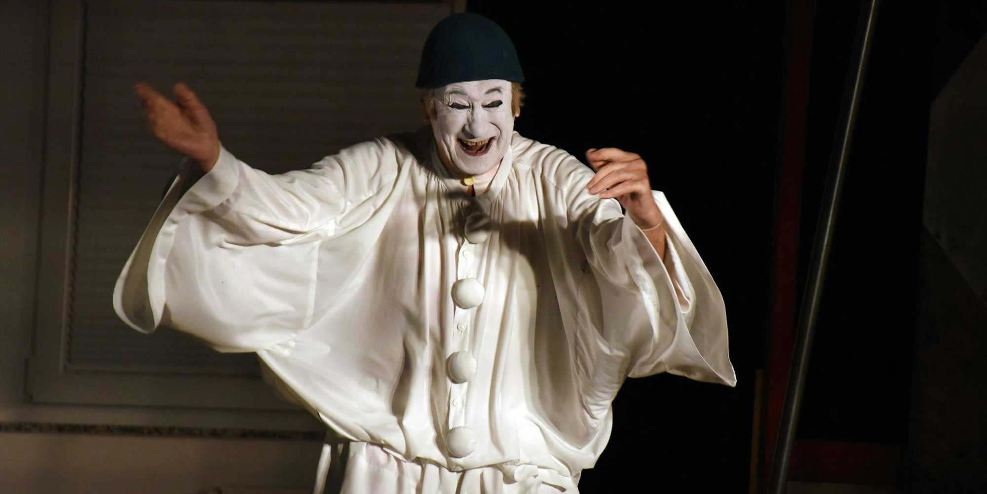 Milan Sládek steht in weißer Pantomime-Kleidung und weiß bemalten Gesicht lachend da.
