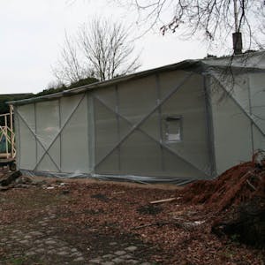 Eine Art Zelt wird um den Waggon errichtet. Im Hintergrund sieht man das Gerüst, das noch mit Planen bespannt wird.
