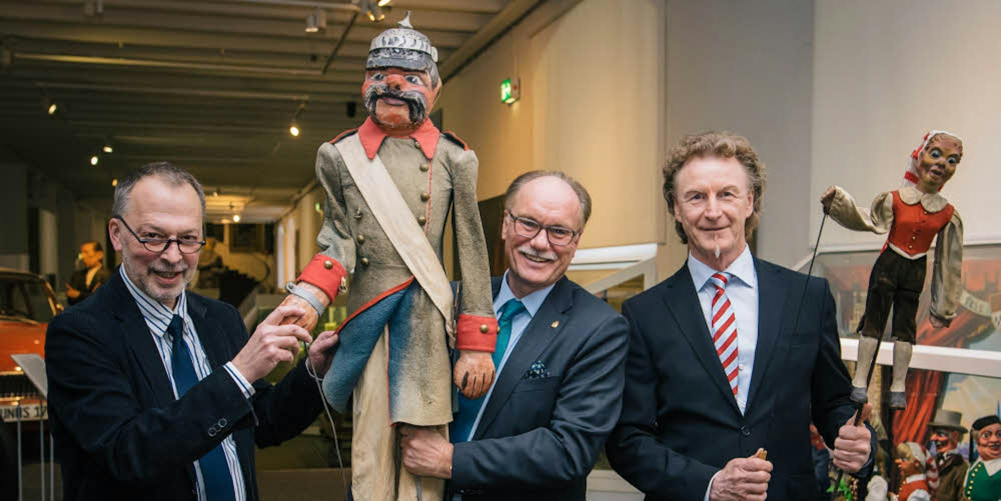 Wieder in Köln: Hennes Lenker (r.) ersteigerte die beiden Stockpuppen im Ruhrgebiet, Bernhard Conin von den Freunden und Förderern des Kölnischen Brauchtums überreichte die Figuren nun Michael Euler-Schmidt (l.) vom Stadtmuseum.