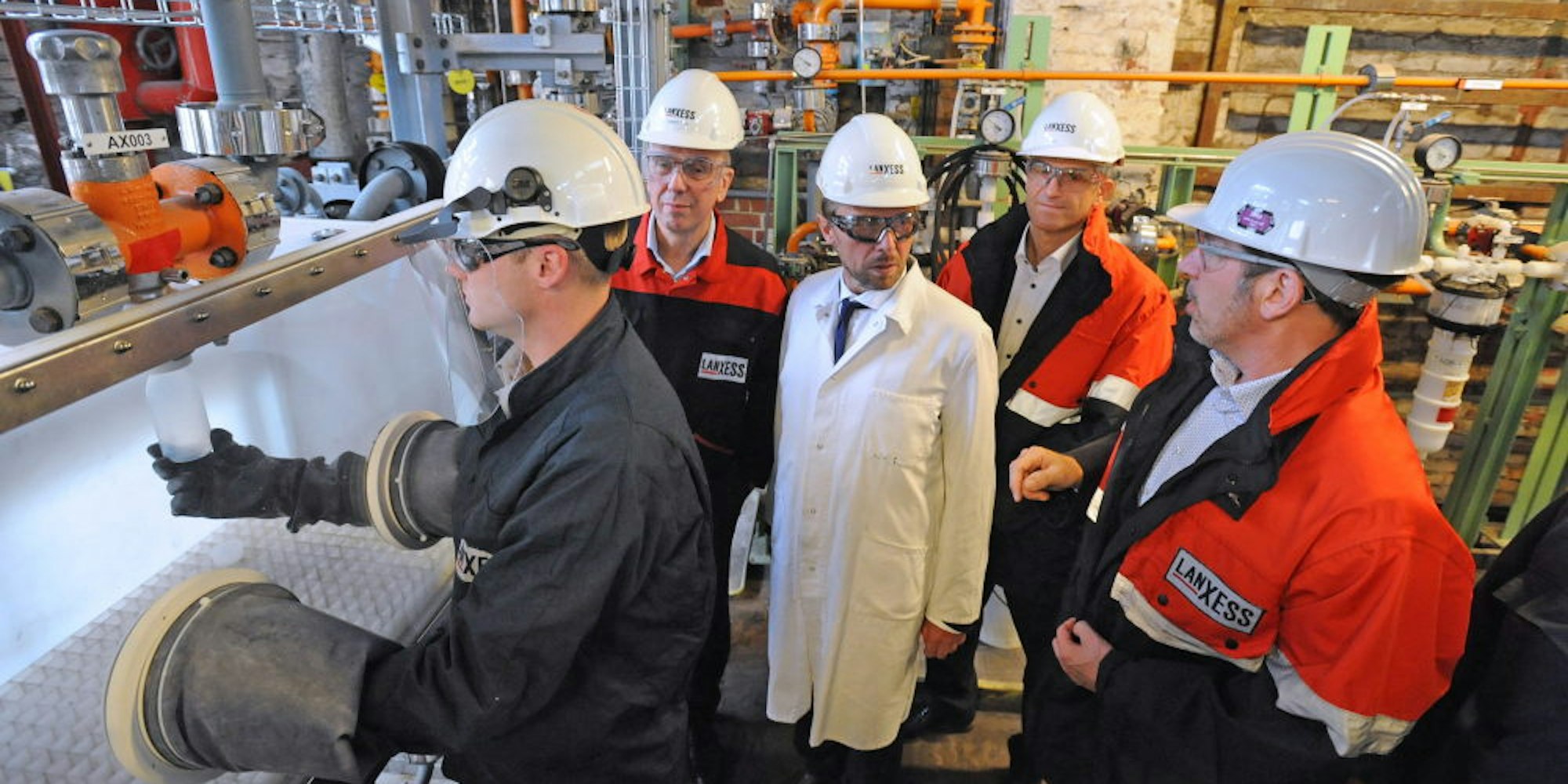 Hubert Fink, Oberbürgermeister Uwe Richrath, Michael Ertl und Thomas Hellmich (v. links) schauen beim Umfüllen von Schwefelsäure zu.