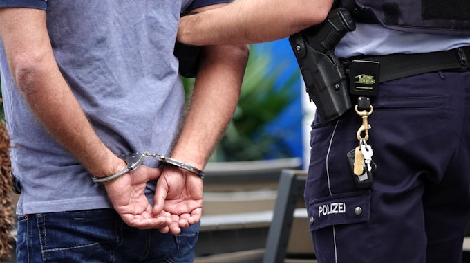 Ein Polizist legt einem Mann Handschellen an.