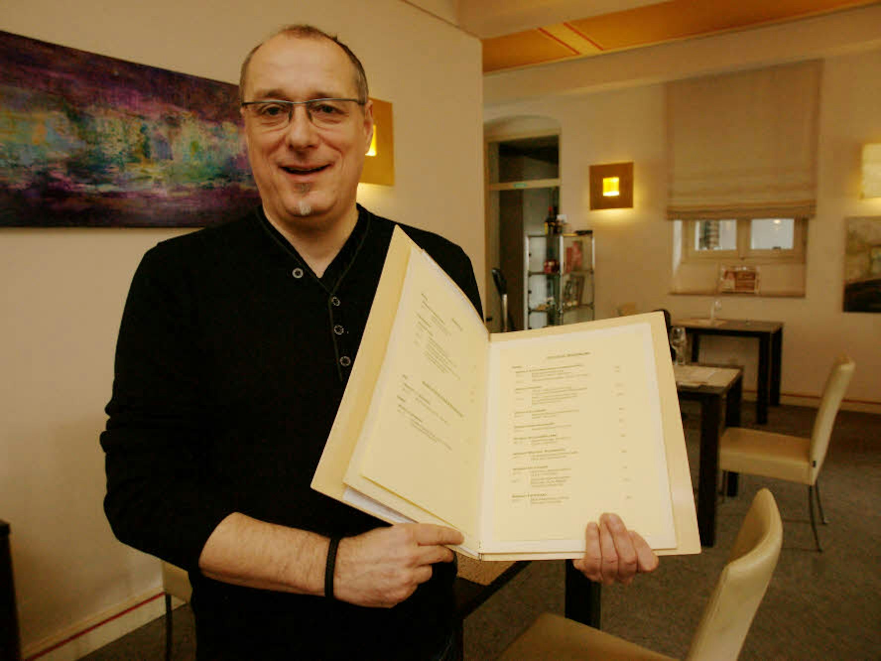 Eine Karte mit einer Liste erlesener Weine zeigt Küchenchef Herbert Brockel in seinem Restaurant, das bewusst jung, modern und puristisch eingerichtet ist.