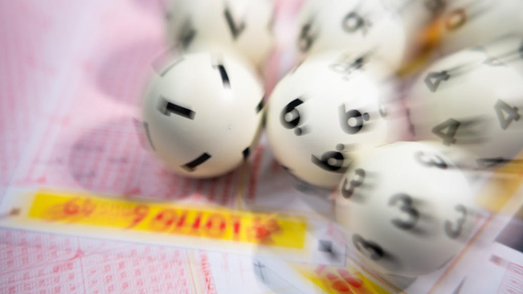 Lottokugeln liegen auf Tippschein