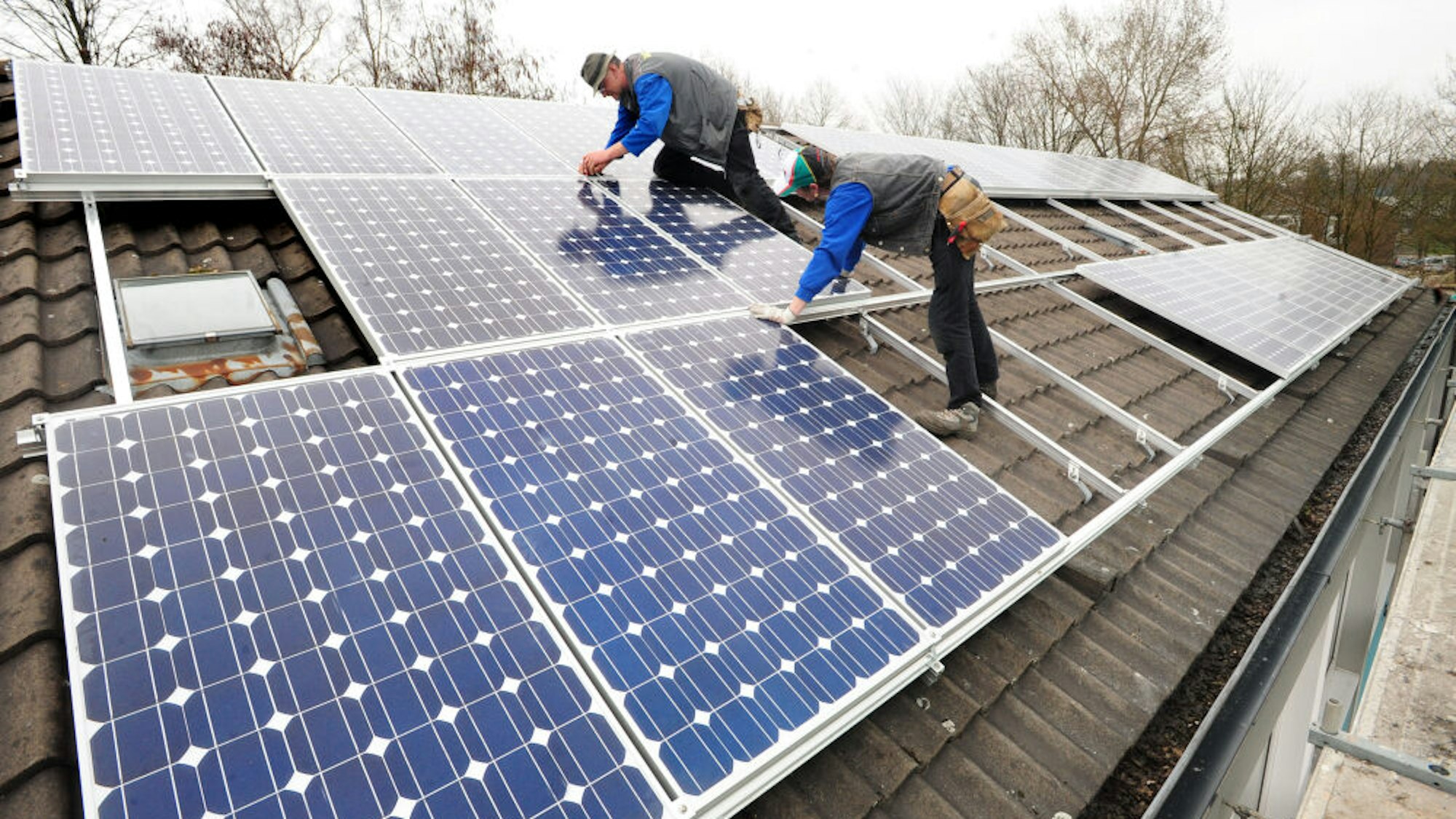 Handwerker montieren Paneele einer Solaranlage auf einem Dach.