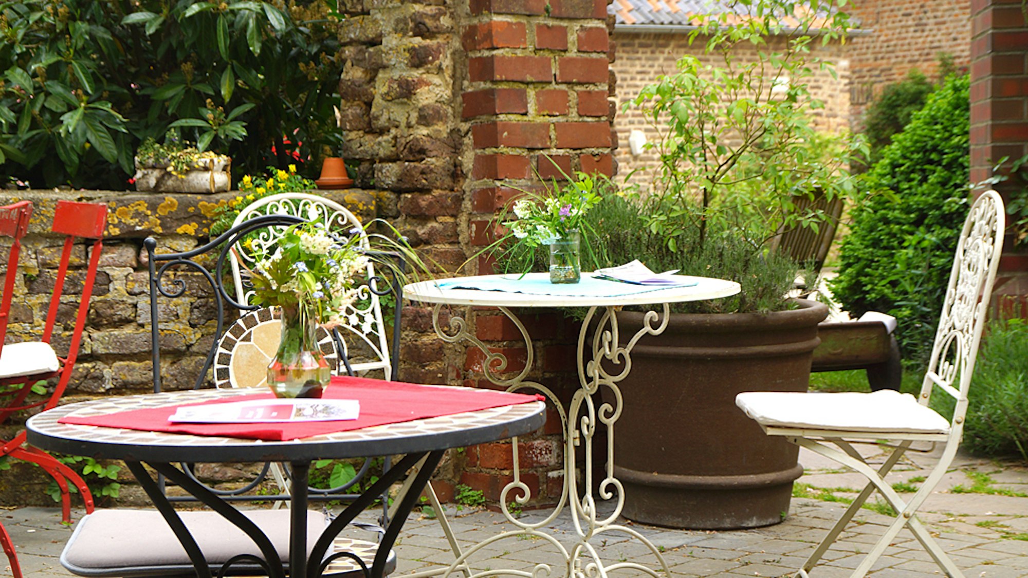 Gartentische und -stühle aus Metall stehen in einem Innenhof