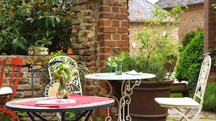 Gartentische und Stühle aus Metall stehen in einem Innenhof