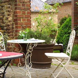 Gartentische und Stühle aus Metall stehen in einem Innenhof