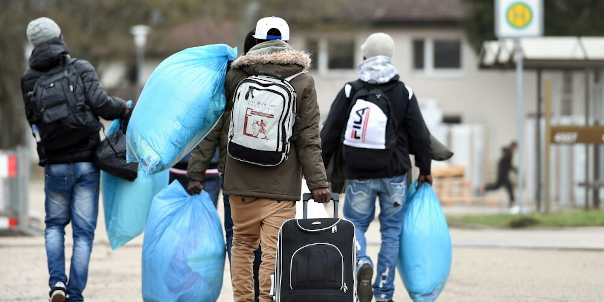 Flüchtlinge tragen ihr Gepäck in eine Unterkunft.