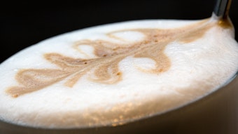 Ein Kaffee mit Kaffee-Kunst im Milchschaum von Nahem