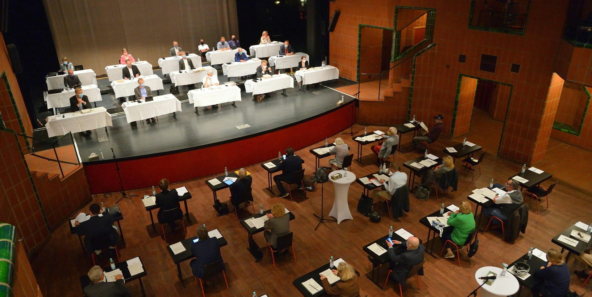 Ratssitzung in Gladbach unter Corona-Bedingungen: Die Verwaltung sitzt an an weißen Tischen auf der Bühne, die Politik im Zuschauersaal.