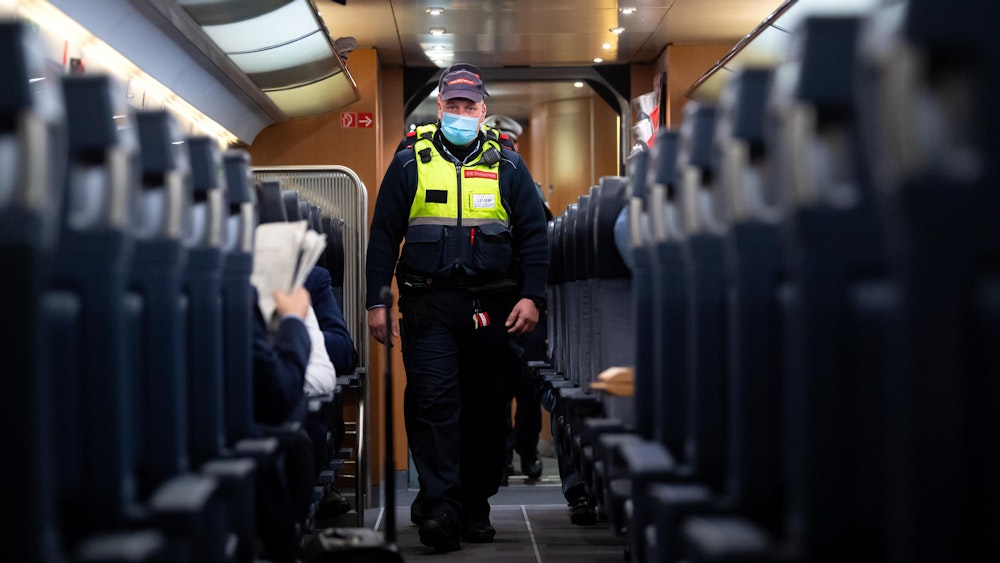 Das undatierte Symbolfoto zeigt einen Polizisten, der durch einen Zug läuft.