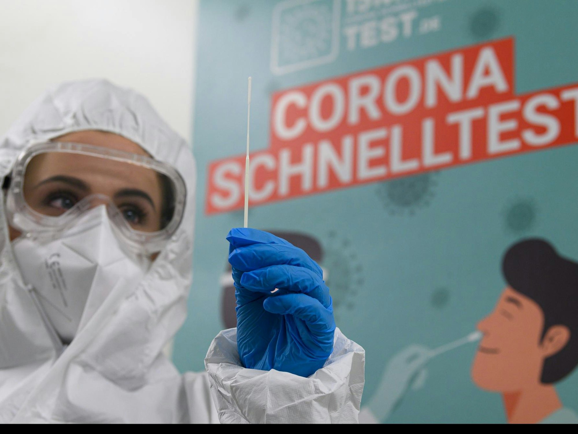 Mitarbeiterin in Schutzanzug bereitet Corona-Test vor