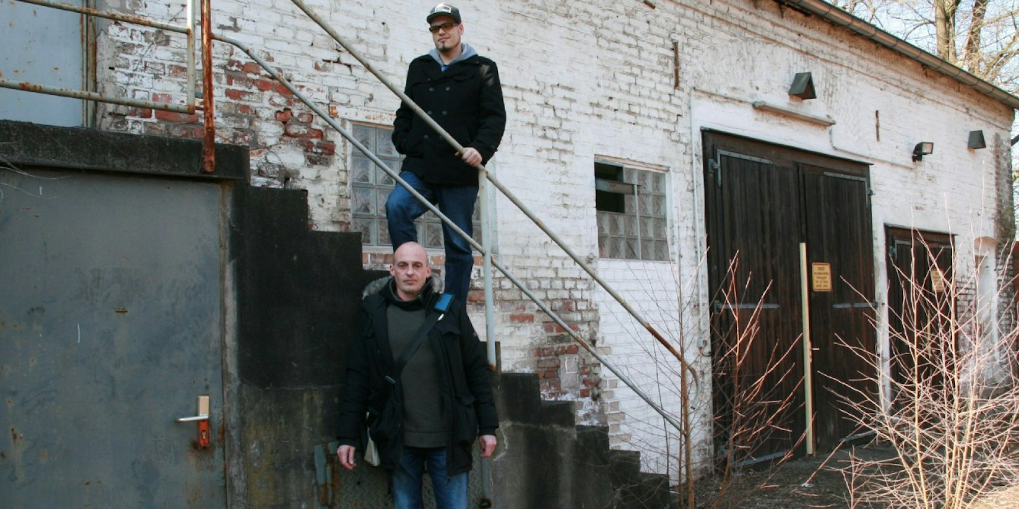 Stephan Teine (unten) und Andreas Marcellus Schwarte vor dem verfallenden Haus, in dem eine hölzerne Treppe ins obere Geschoss führt.