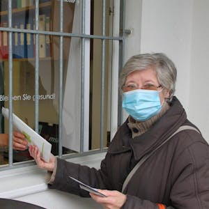 Das Fenster zum Hof ist in der Mechernicher Adler Apotheke die Ausgabestelle für die Schutzmasken. Gabriele Lock erhält hier von Alena Leesch ihr Dreier-Set.