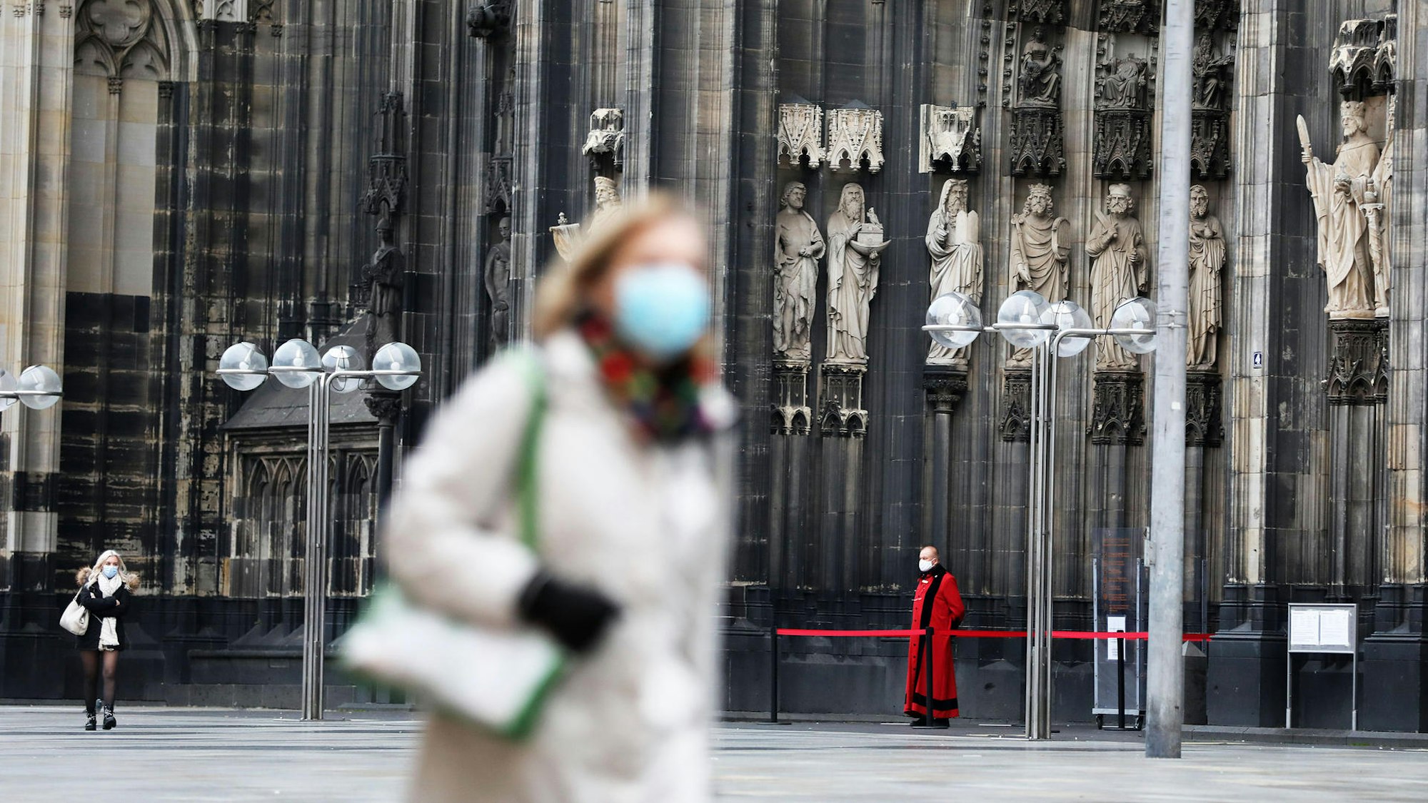 Eine Frau mit Corona-Maske vor dem Kölner Dom