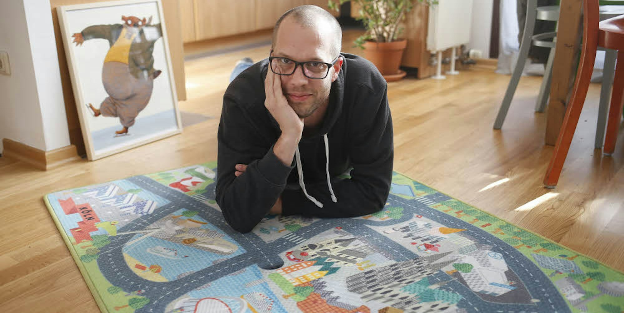 Matthias Schindlbeck auf dem Kinderteppich mit Köln-Motiven