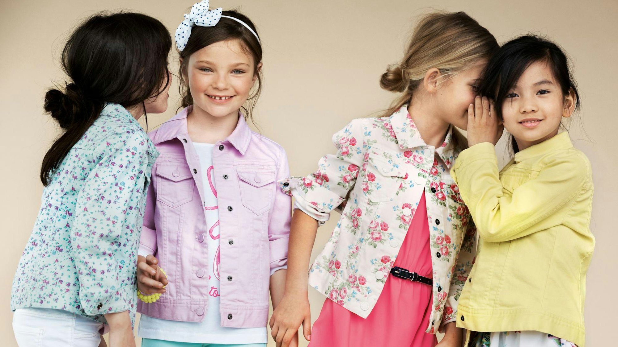 Benetton Werbebild mit vier kleinen Mädchen, die sich etwas zuflüstern