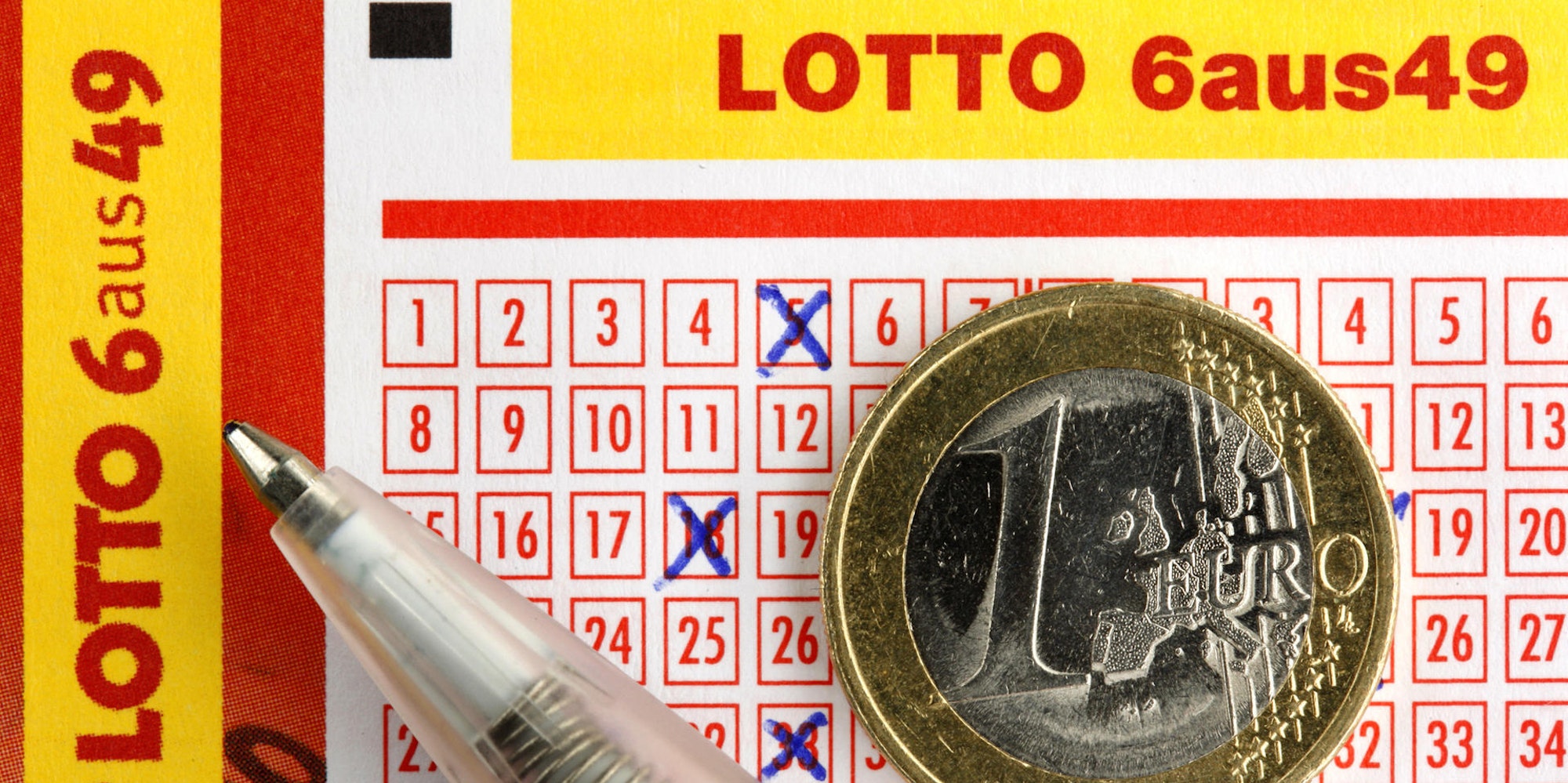 Euro-Münze liegt auf ausgefülltem Lottoschein