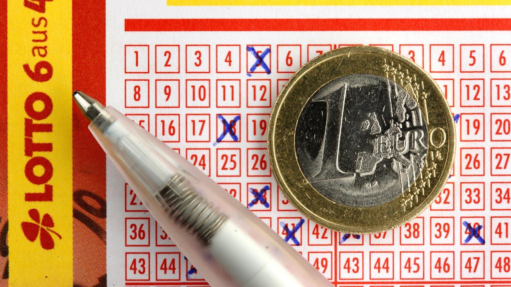 Euro-Münze liegt auf ausgefülltem Lottoschein