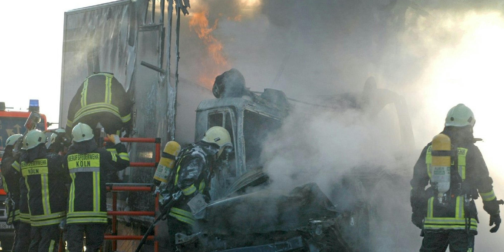Feuerwehrleute löschen am Montag auf der A4 bei Köln brennende Fahrzeuge.