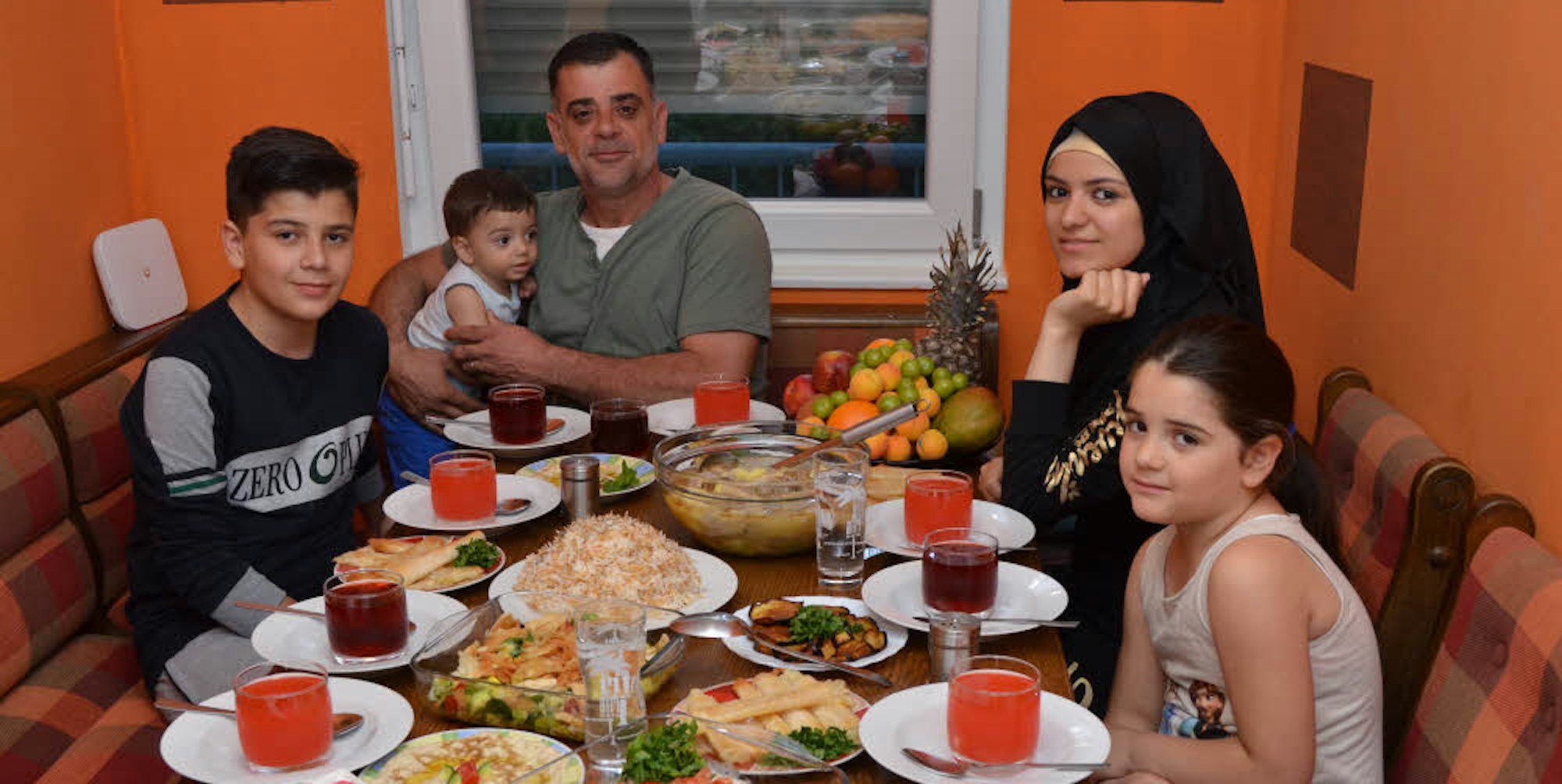 Fastenbrechen im Ramadan: Anoar Abo Harb (mit Kopftuch) und ihr Bruder Yassin,Vater Jamil Abo Harb und Schwester Nezma sitzen am reich gedeckten Tisch in ihrer Wohnung in der Flüchtlingsunterkunft in Siegburg.