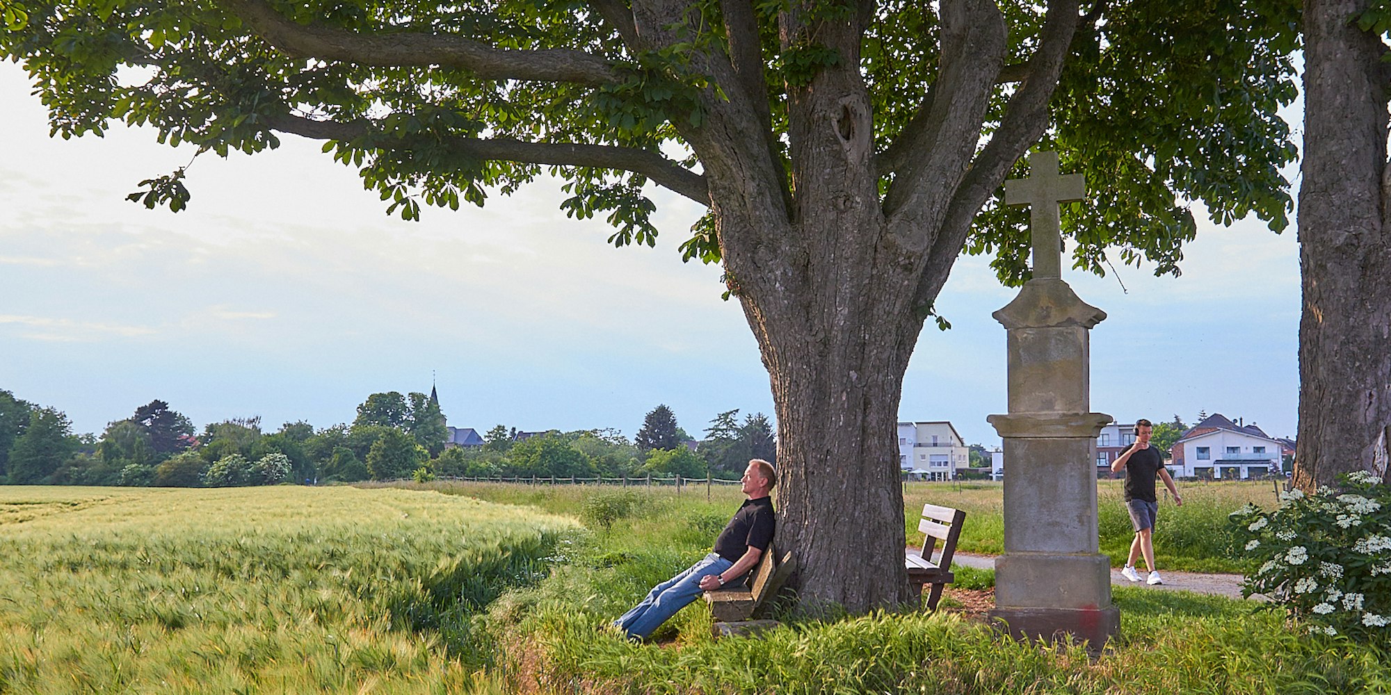 Ein Mann sitzt unter einem Baum auf einer Bank