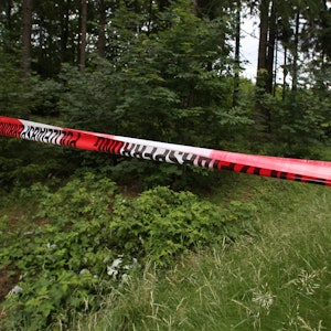 Das Foto zeigt einen mit Polizei-Flatterband abgesperrten Bereich in einem Waldstück.