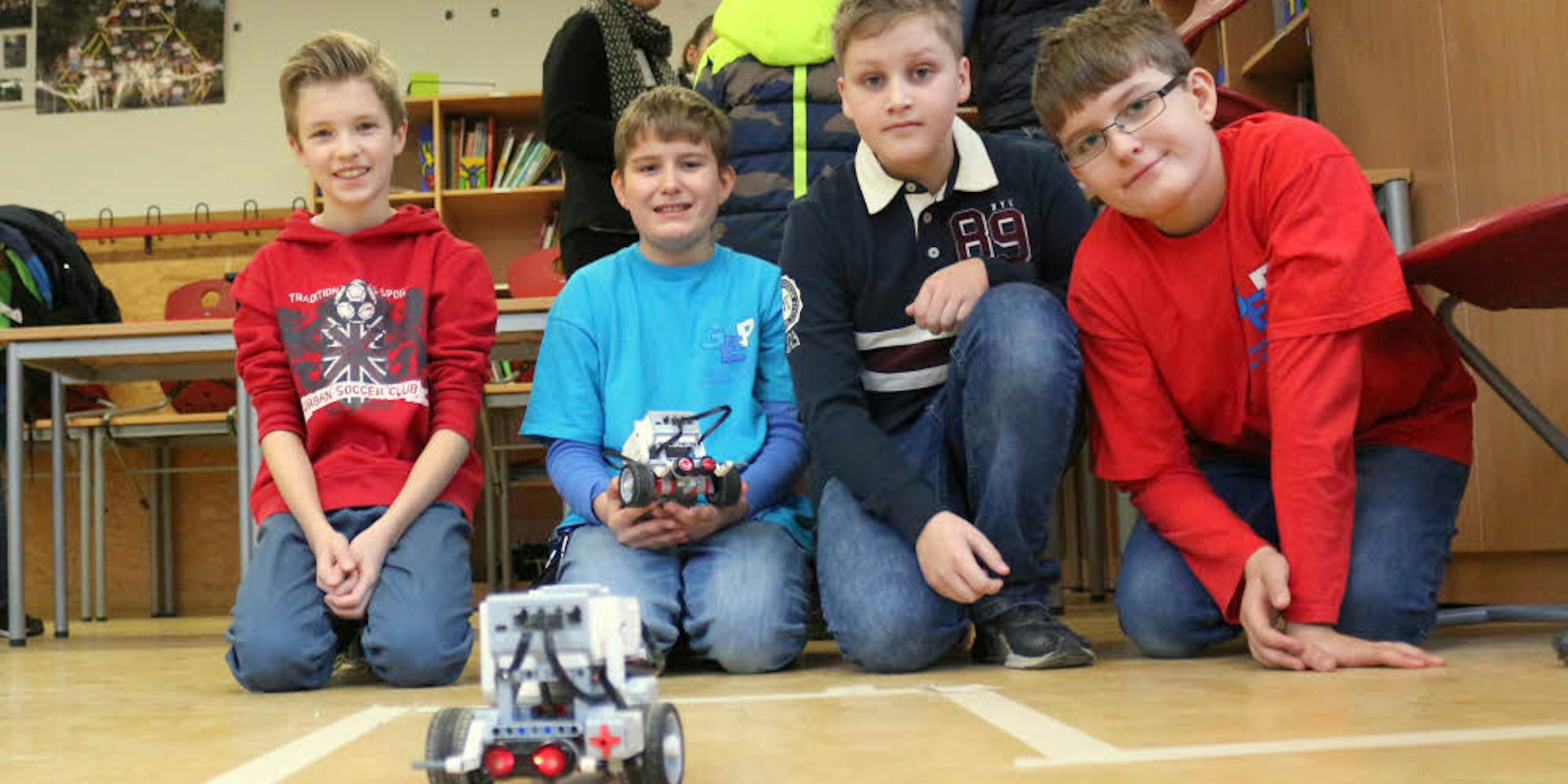 Jonas Jung (2. v. r.) gibt seine Kenntnisse an die Mitschüler weiter – sie programmieren gemeinsam Lego-Roboter.