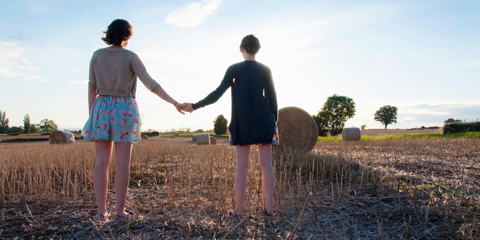 Zwei Frauen stehen auf einem Feld und halten sich an der Hand.