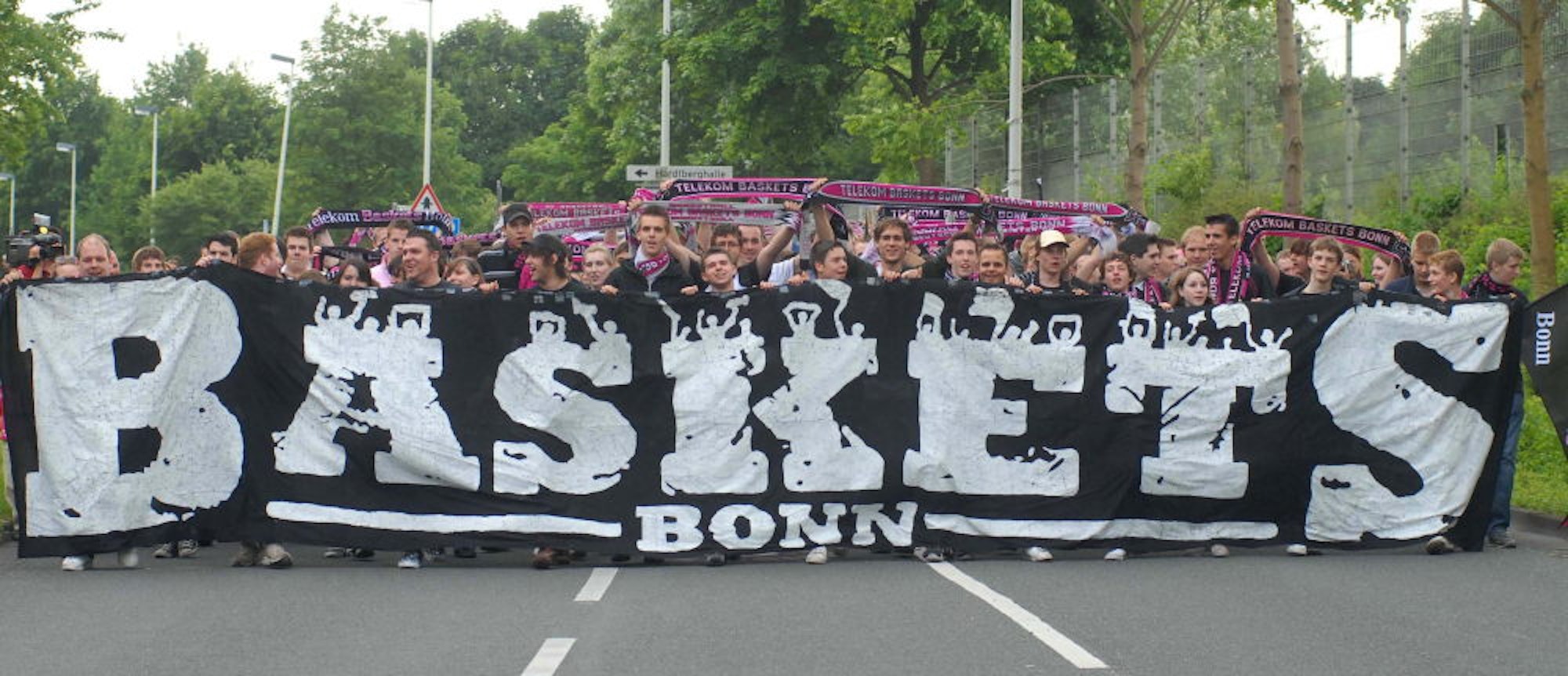 Vor der ersten Partie ziehen Fans mit einem breiten Banner von der Hardtberghalle zum Telekom Dome, um den „Baskets-Spirit“  in die nagelneue  Arena zu transportieren.