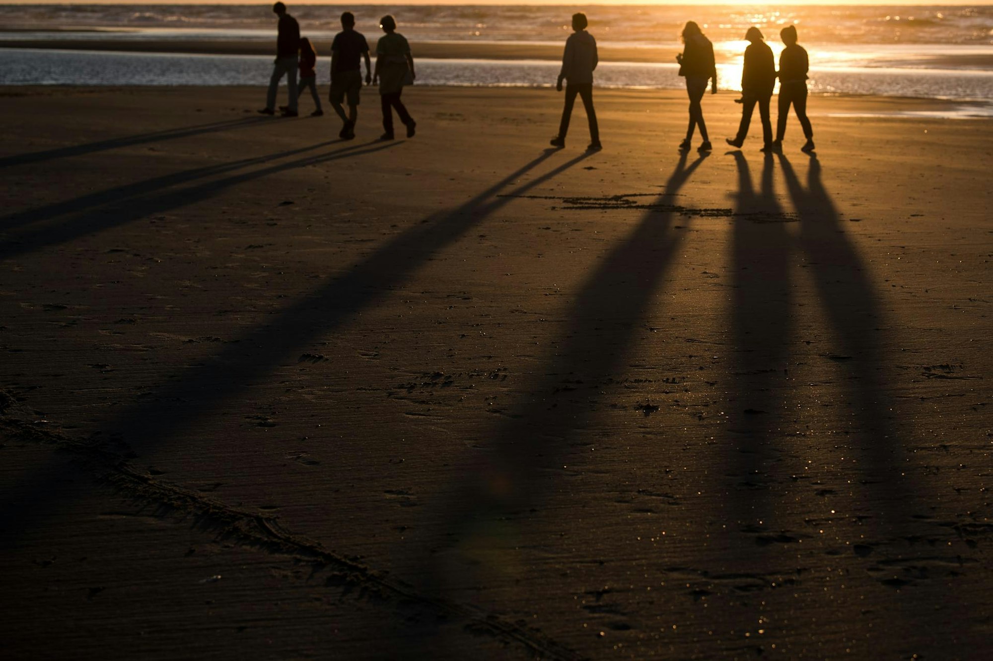 Spaziergänger bei Sonnenuntergang am Strand
