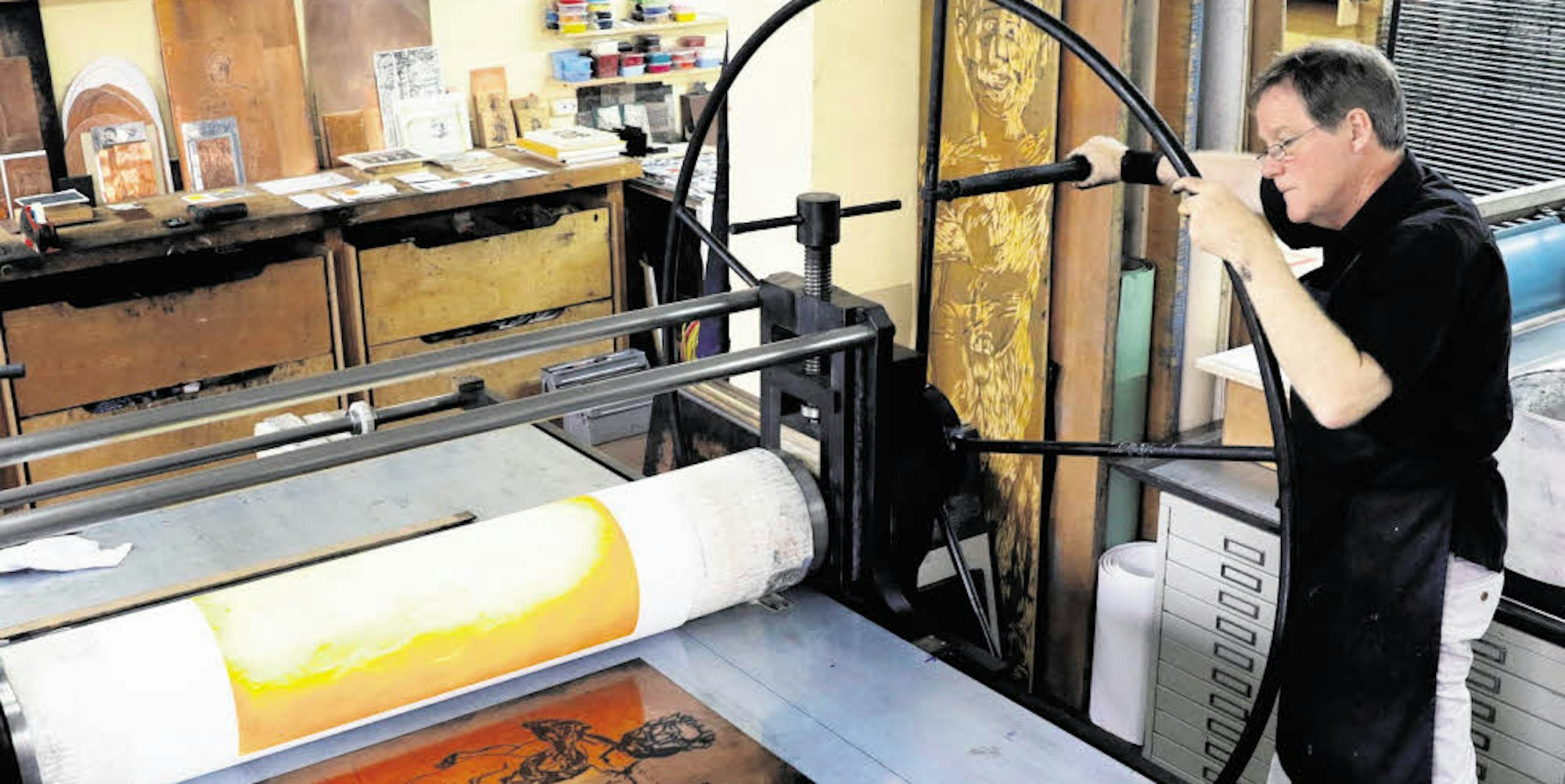 Der Kunstdrucker bei der Arbeit an seiner Radierpresse.