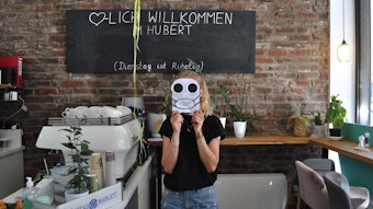 Kyria Möbius im Café Hubert hält sich ein Eulenmaskottchen vors Gesicht