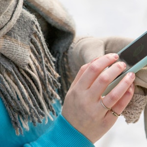 Eine Frau hält im Winter ein Handy in ihrer Hand.