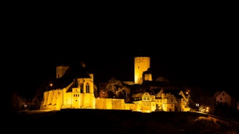 Burganlage bei Nacht in goldenem Licht angeleuchtet
