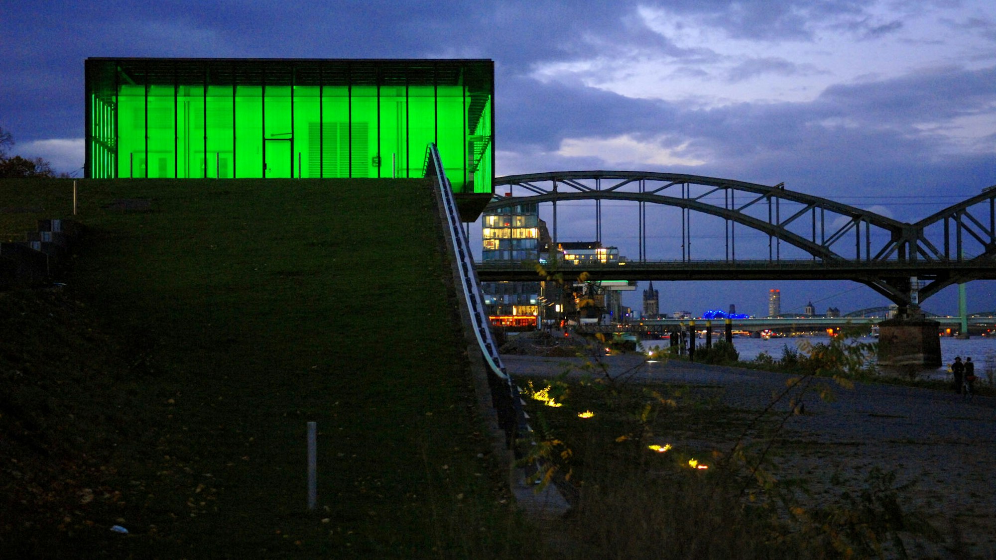 grün beleuchtetes Gebäude in der Dämmerung, Brücke im Hintergrund