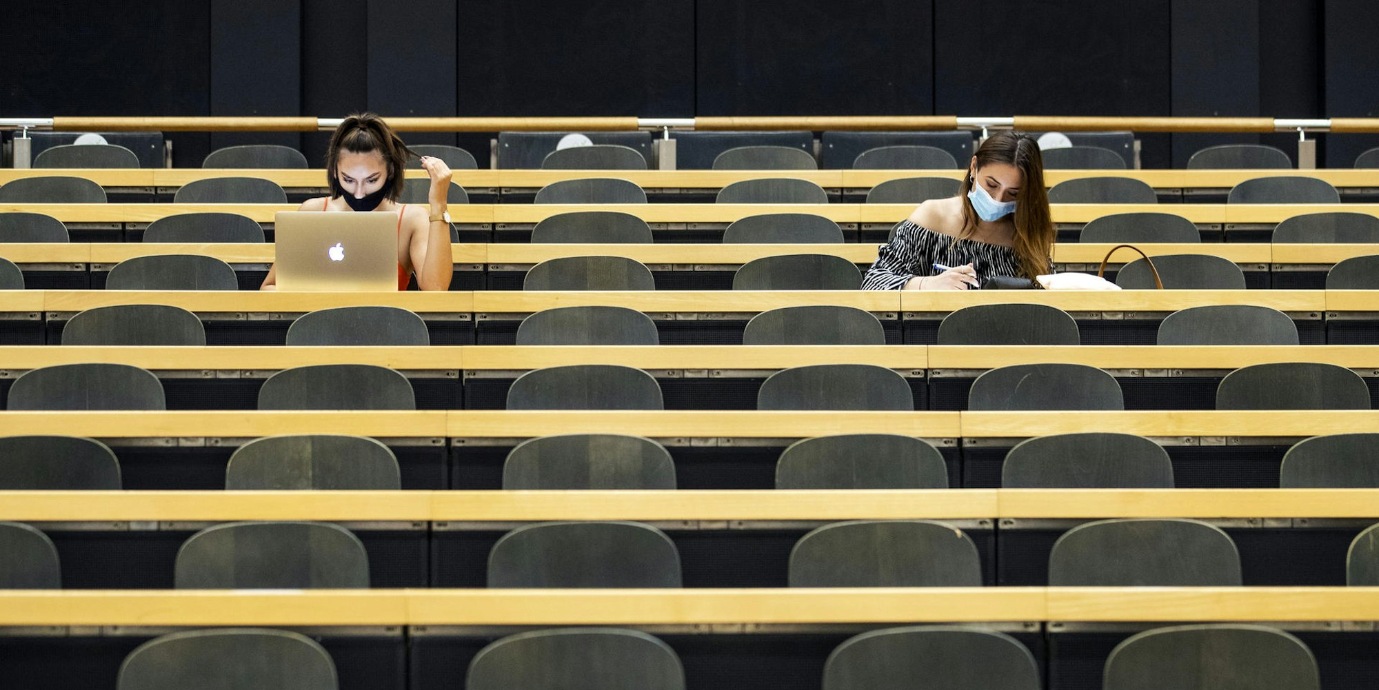 Studentinnen mit Mund-Nasen-Schutz sitzen in einem Hörsaal 