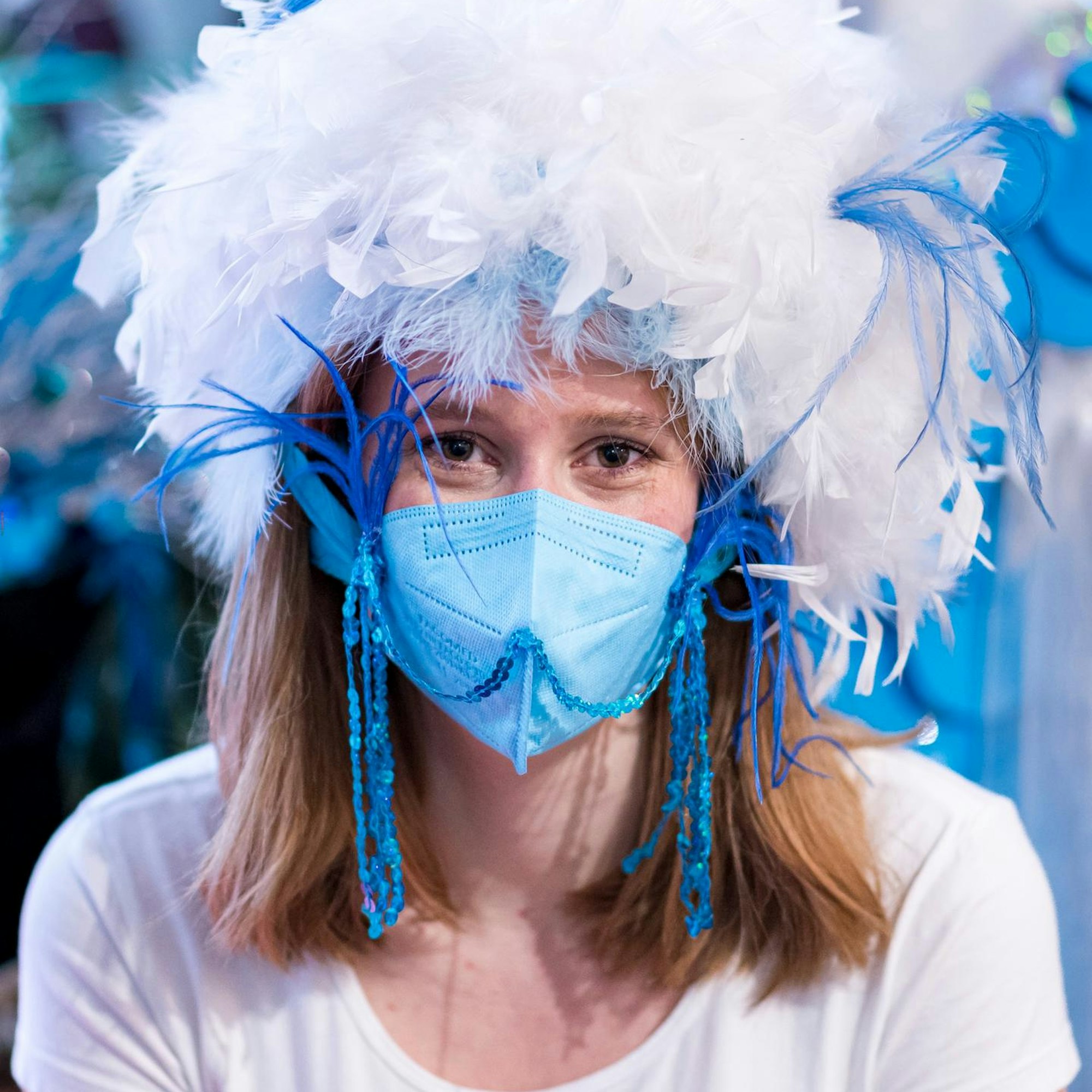 Mit Federn und Pailletten wird die blaue FFP2-Maske zum karnevalistischen Hingucker.