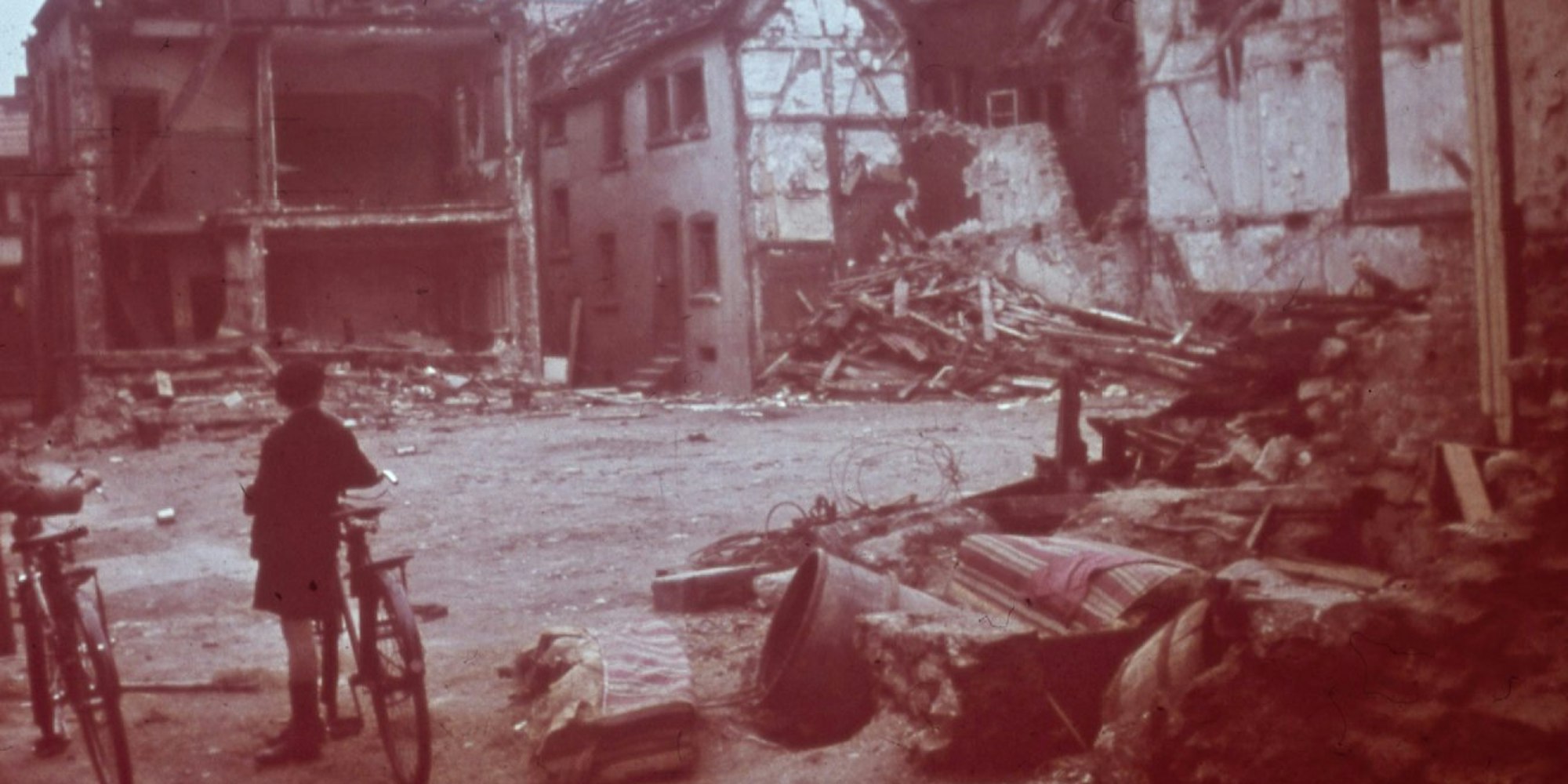 Zwei Jungen mit Fahrrädern, umgeben von Trümmern. Im Laufe des Krieges wurde die Stadt Köln insgesamt 262-mal bombardiert – mehr als jede andere deutsche Stadt – 31-mal davon schwer.