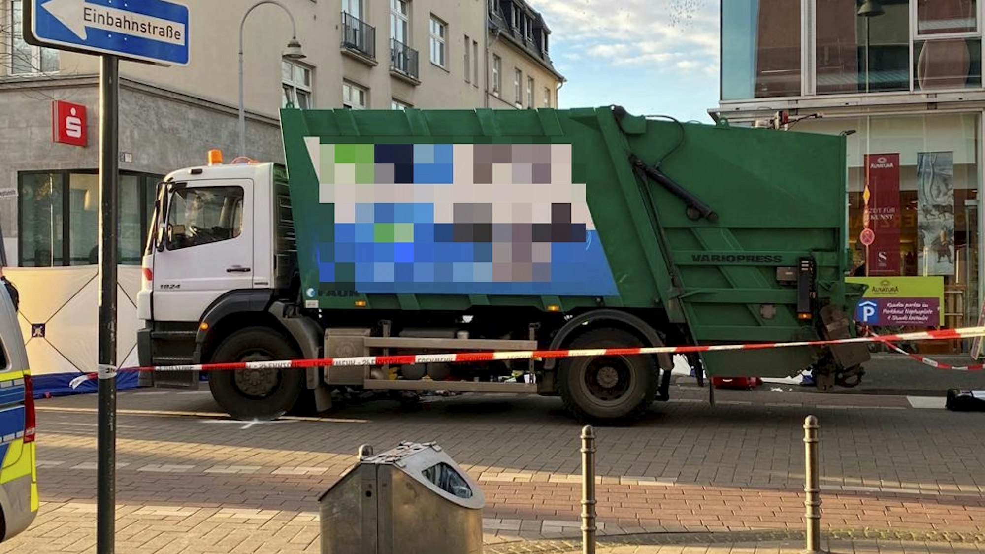 Ein Müllwagen steht auf der Straße, davor ist Absperrband der Polizei gespannt.